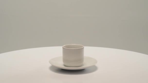 白色底座上有咖啡杯的白色茶托在桌子上旋转 — 图库视频影像