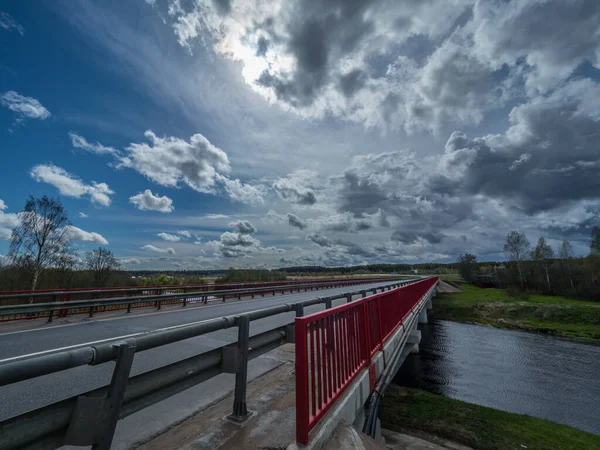 Road bridge over the river under a stormy sky. The road that goes over the horizon.
