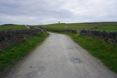 Yan tarafta taş duvarlara sahip bir çakıl yolu
