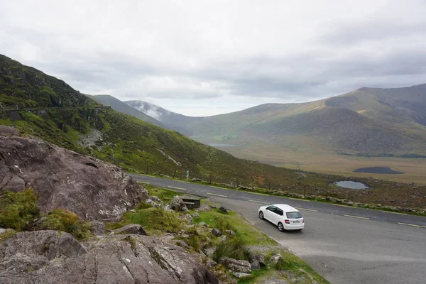 Irlanda 'da bir dağ yolu aşağı gidiyor beyaz bir araba