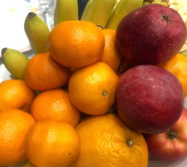 Mandarin, kırmızı elma ve muz tabakta.