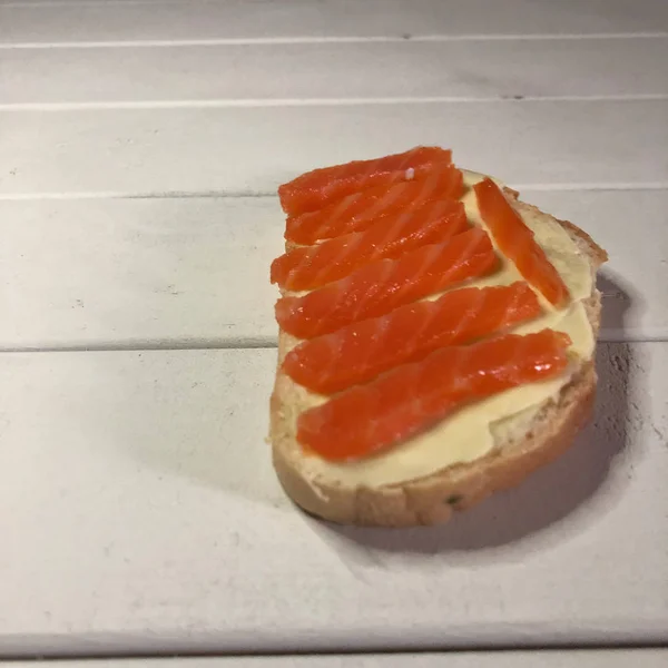 Sanduíche com peixe vermelho sobre um fundo de madeira branco — Fotografia de Stock