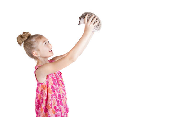A young girl holding her pet hedgehog up in the air
