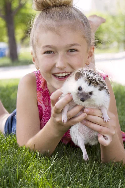 Young girl holding a pet hedgehog outside — Stock Photo, Image