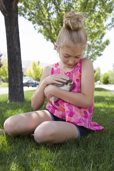 Young girl holding a pet hedgehog outside — Stock Photo, Image
