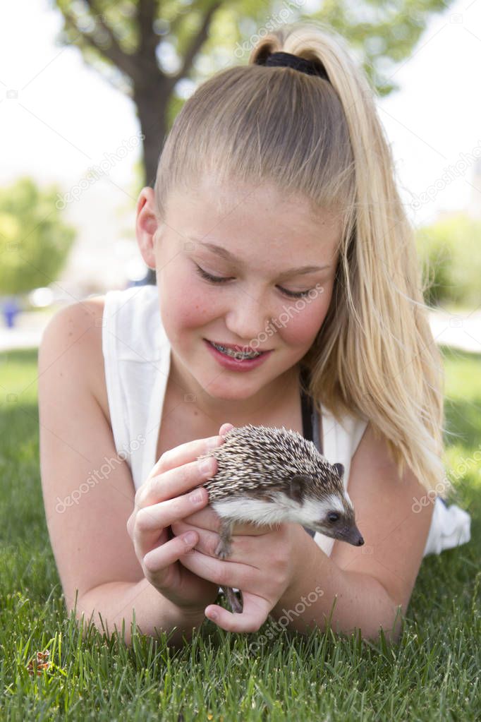 Young teen girl holding a pet hedgehog outside 