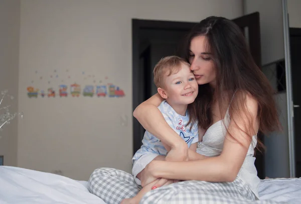 Matka przytula syna na łóżku — Zdjęcie stockowe