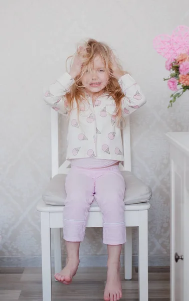 어린 소녀가 금발 그녀의 핑크 파자마 상단에의 자에 앉아, 머리에 혼란을 일으키는 — 스톡 사진