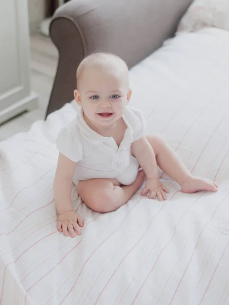 Retrato de un bebé sentado en una cama grande, estilo de vida Imagen de stock