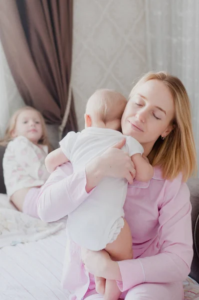 Matka posiada jako najmłodsze dziecko w ramionach, a najstarsza córka siedzi z boku, jeden — Zdjęcie stockowe