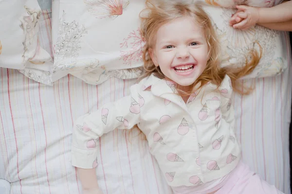 Petite fille riant couché sur le lit — Photo