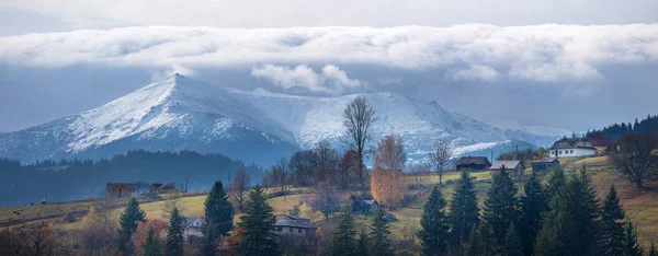 Egy hegyi falu, az ősz Kárpátokban, a háttérben hófödte hegyek panoráma fotó. — Stock Fotó