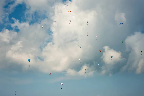 Velká skupina paraglidisty létají na obloze na pozadí mraků. — Stock fotografie