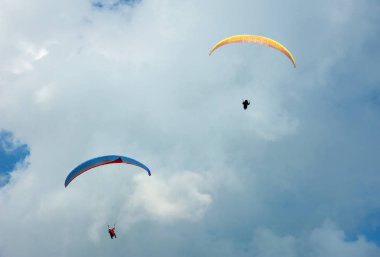 İki paraşütler bulutlar arka planı mavi gökyüzünde uçan.