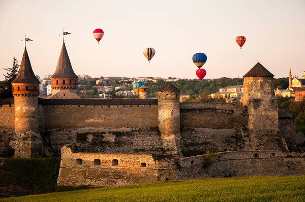 Striped hot air balloon flying over castle. 