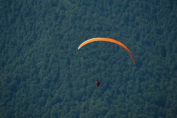 Een paraglider vliegt over een bergdal op een zonnige zomerdag. — Stockfoto