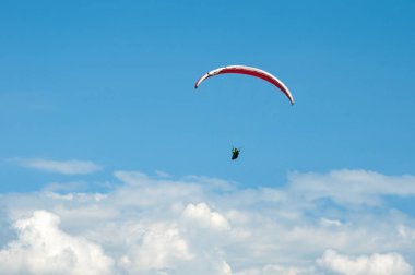 Bulutlar arka planı mavi gökyüzünde uçan Yamaçparaşütü.