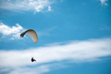 Bulutlar arka planı mavi gökyüzünde uçan Yamaçparaşütü.