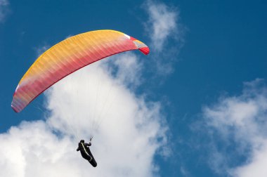 Bulutlar arka planı mavi gökyüzünde uçan Yamaçparaşütü.