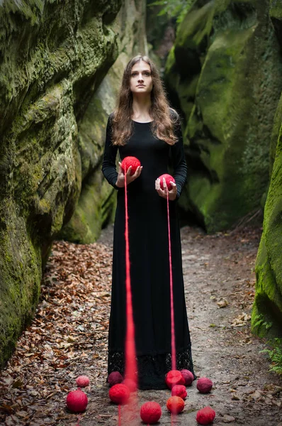 Bir esmer siyah elbiseli, kayaların duruyor ve elinde tutar portresi.