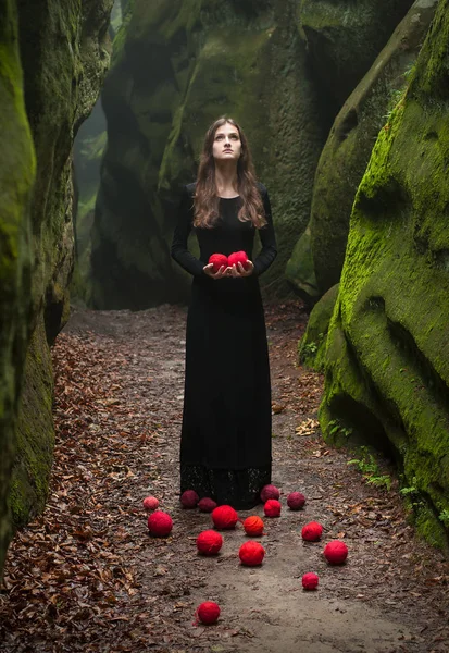 Bir esmer siyah elbiseli, kayaların duruyor ve elinde tutar portresi.