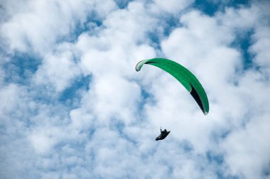 Bulutlar arka planı mavi gökyüzünde uçan Yamaçparaşütü. 
