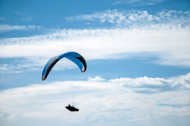 Bulutlar arka planı mavi gökyüzünde uçan Yamaçparaşütü. 