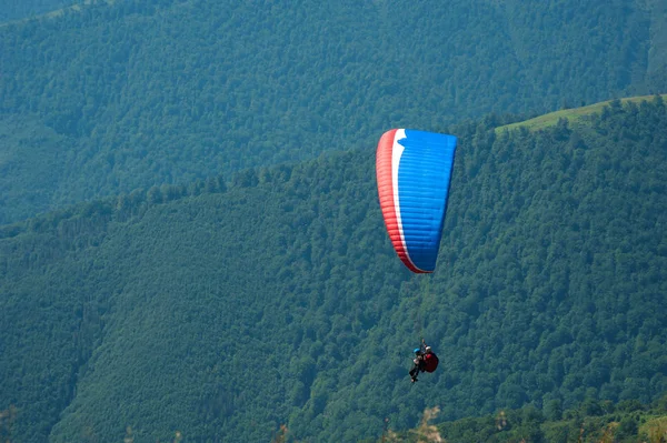 Αλεξίπτωτο που πετά πάνω από την κοιλάδα του βουνού σε μια ηλιόλουστη καλοκαιρινή μέρα — Φωτογραφία Αρχείου