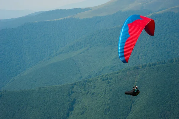 Parapente survole une vallée de montagne par une journée d'été ensoleillée — Photo