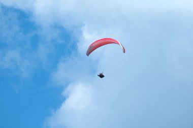 Bulutlar arka planı mavi gökyüzünde uçan Yamaçparaşütü.