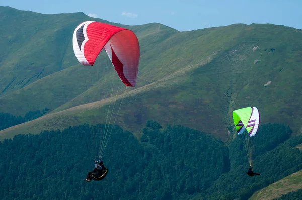 Δύο αλεξίπτωτα πετούν πάνω από την κοιλάδα στο βουνό μια ηλιόλουστη καλοκαιρινή μέρα. — Φωτογραφία Αρχείου