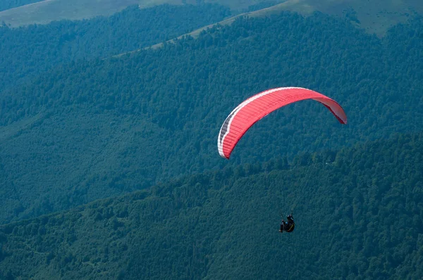 A paraglider flies over a mountain valley on a sunny summer day. — Stock Photo, Image
