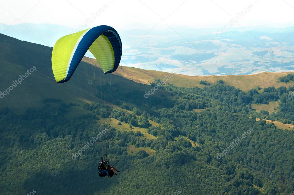 Tandem flies over a mountain valley on a sunny summer day. 