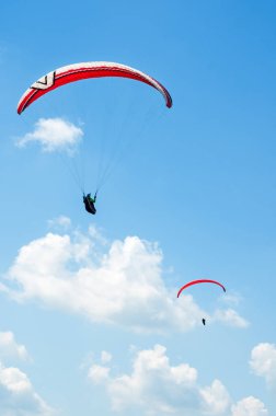 İki paraşütler bulutlar arka planı mavi gökyüzünde uçan. 
