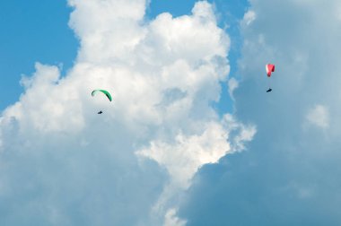 İki paraşütler bulutlar arka planı mavi gökyüzünde uçan. 