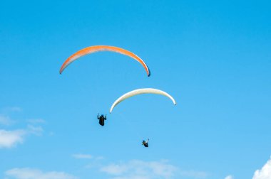İki paraşütler bulutlar arka planı mavi gökyüzünde uçan. 