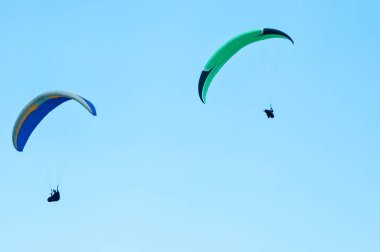 Mavi gökyüzünde uçan iki paraşütler. 