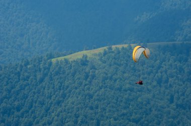 Yamaçparaşütü dağ Vadisi bir güneşli yaz gününde uçar.. 
