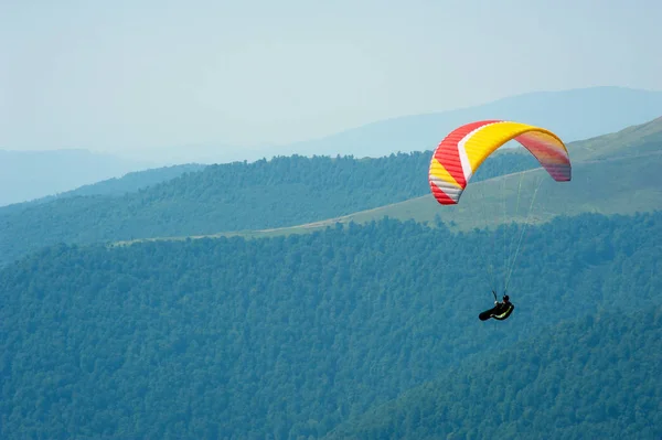 Αλεξίπτωτο που πετά πάνω από την κοιλάδα του βουνού σε μια ηλιόλουστη καλοκαιρινή μέρα. — Φωτογραφία Αρχείου