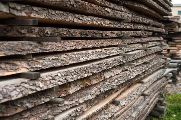 Folded wooden brown and gray planks in a sawmill. Piled alder bo — Stock Photo, Image