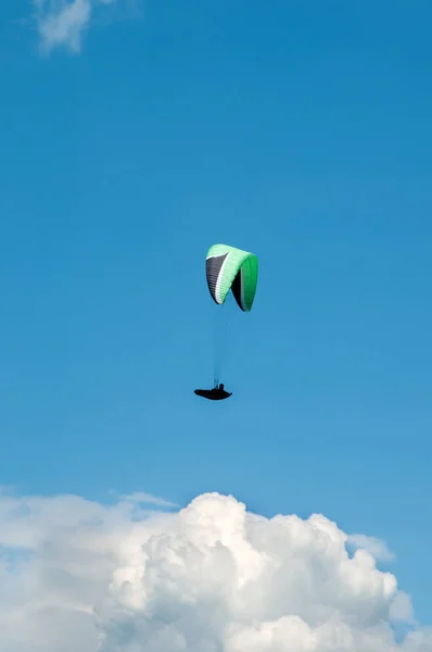 Ensam paraglider flyger i den blå himlen mot bakgrund av moln. — Stockfoto