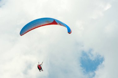 Yalnız Yamaçparaşütü bulutlar arka planı mavi gökyüzünde uçan.