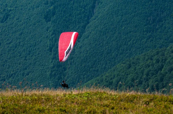 Αλεξίπτωτο που πετά πάνω από την κοιλάδα του βουνού σε μια ηλιόλουστη καλοκαιρινή μέρα. P — Φωτογραφία Αρχείου