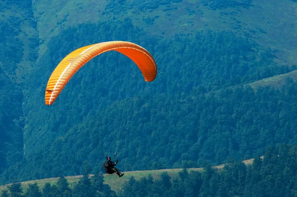 Gleitschirm fliegt an einem sonnigen Sommertag über einem Gebirgstal. p — Stockfoto