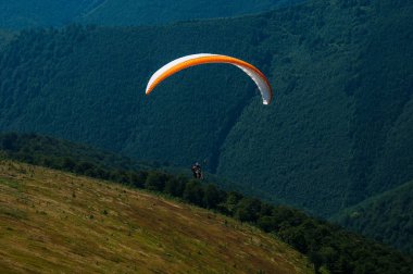 Yamaçparaşütü dağ Vadisi bir güneşli yaz gününde uçar.. 