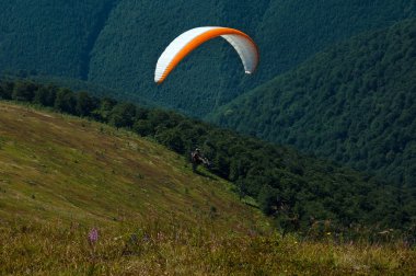 Yamaçparaşütü dağ Vadisi bir güneşli yaz gününde uçar.. 