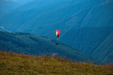 Yamaçparaşütü dağ Vadisi bir güneşli yaz gününde uçar.. 