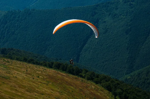 Parapente survole une vallée de montagne par une journée d'été ensoleillée . — Photo