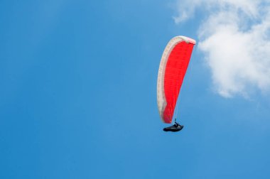 Bulutlar arka planı mavi gökyüzünde uçan Yamaçparaşütü.