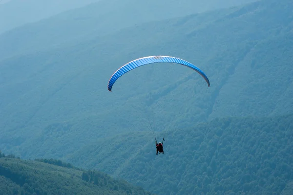 Parapente survole une vallée de montagne par une journée d'été ensoleillée . — Photo